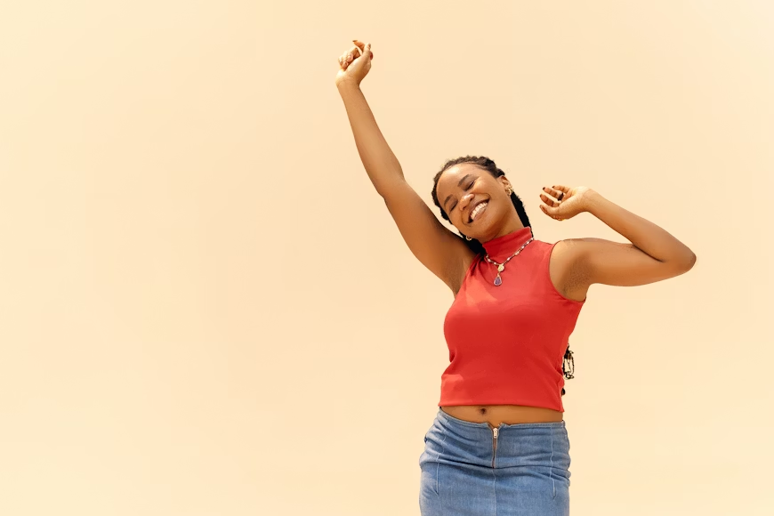 A happy young black woman raising her hands